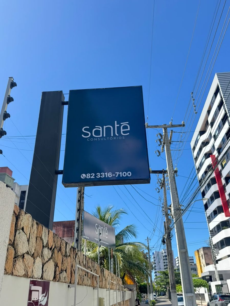 Placa da Santé Consultórios na avenida, com o telefone, vista da calçada
